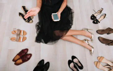 young woman with long legs sitting floor wardrobe with smartphone hands writing message searching internet lot shoes around wearing black beautiful skirt silver stylish high heels 1140x700 1 364x230